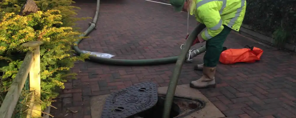 Septic tank cleaning technician servicing a septic tank with a vacuum hose in Royal Oak, MI
